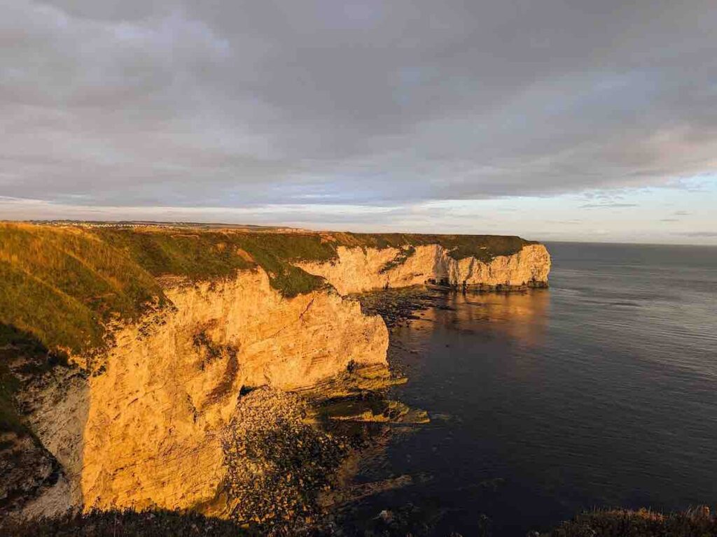 Sun lit Flamborough Head chalk cliffs with the North Sea at low tide