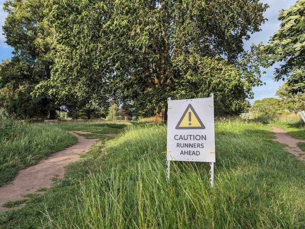 Trail running race route with a sign saying 'Caution runners ahead'
