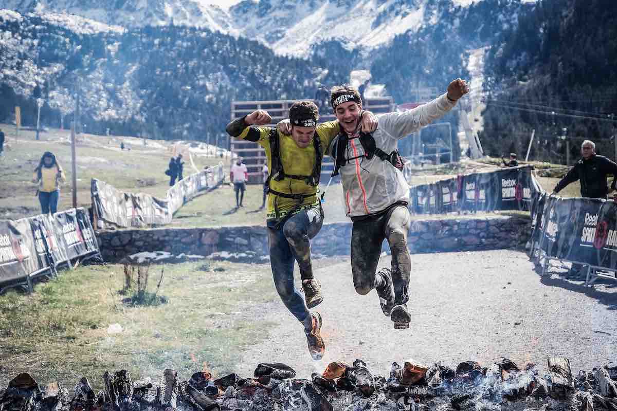 Two happy runners jumping over hot coals at Tough Mudder
